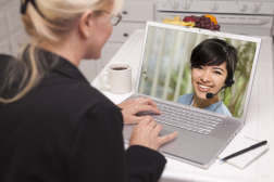 Two women talk, one on screen of laptop computer customer service live video chatting with customer on screen