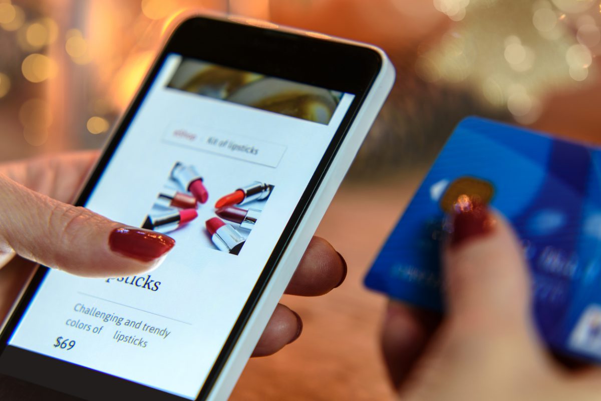 Woman shopping on mobile phone buying lipstick