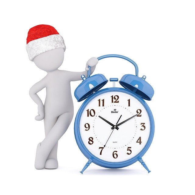 white figure wearing santa hat leaning on blue alarm clock