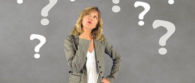 woman in jeans and blazer looking up question marks around her