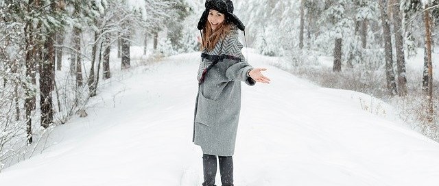 Girl in snow wearing black hat and grey long coat