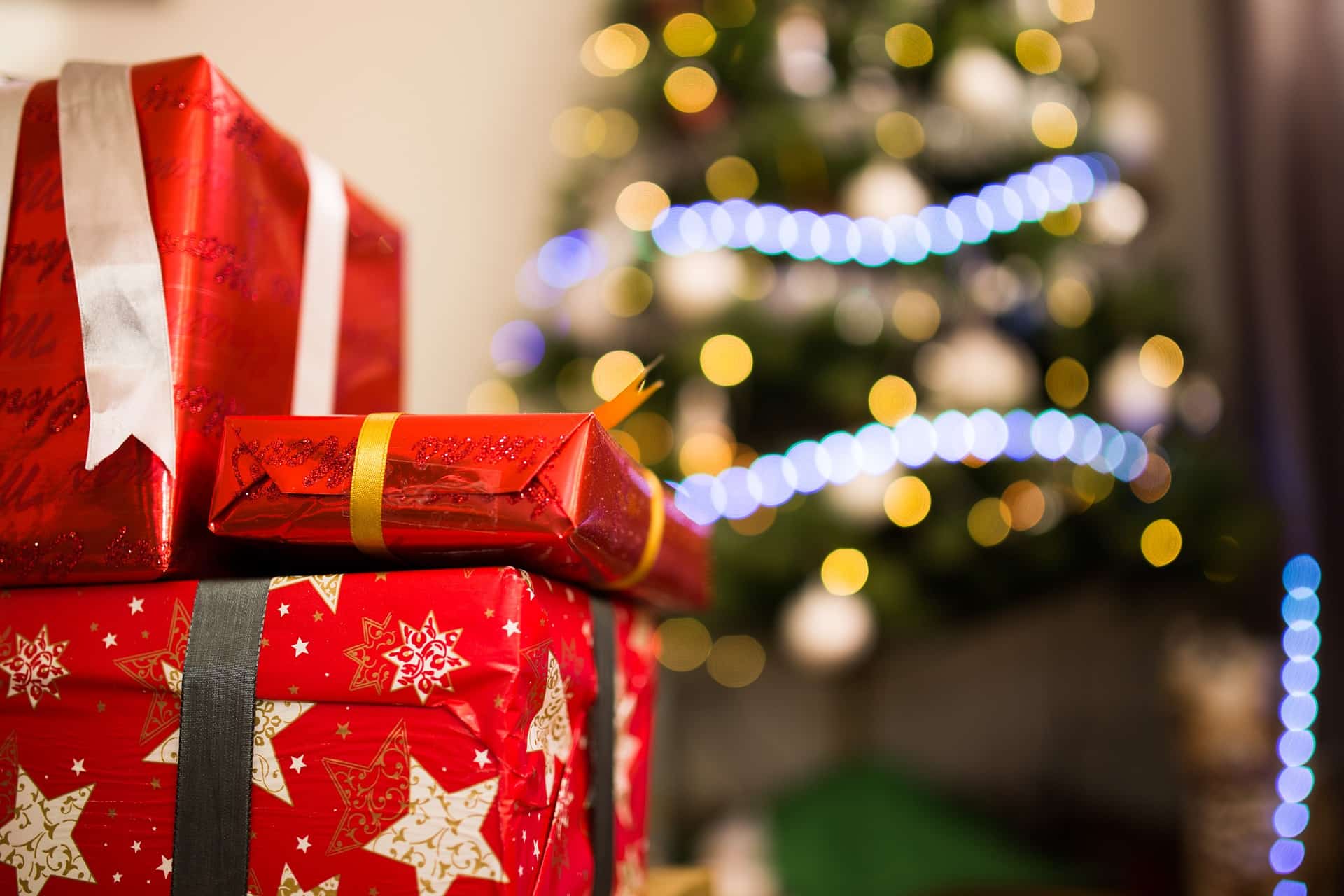red xmas packages in front of xmas tree with lights