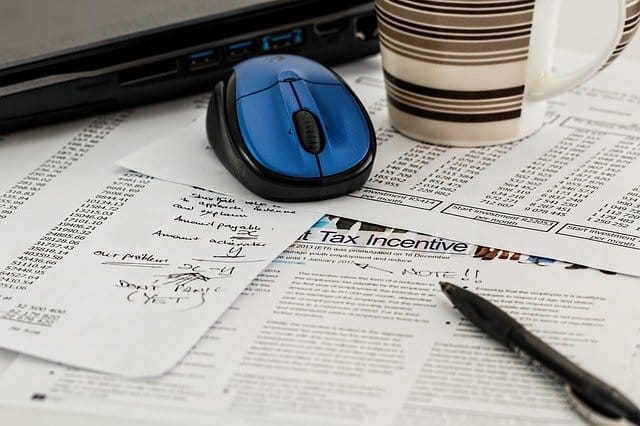 tax forms on desk with blue mouse and coffee mug